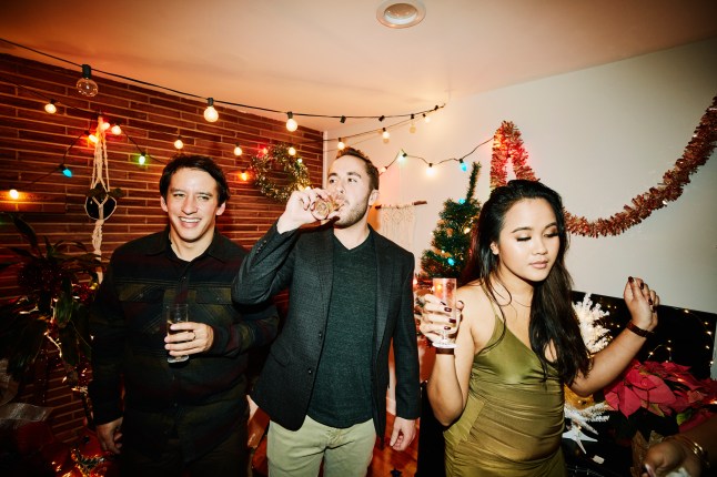 Man drinking champagne while hanging out with friends during holiday party